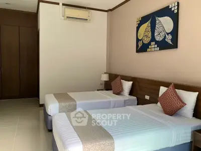 Spacious bedroom with twin beds, modern decor, and ample natural light.
