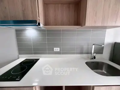 Modern kitchen with sleek induction cooktop and stylish faucet in minimalist design.