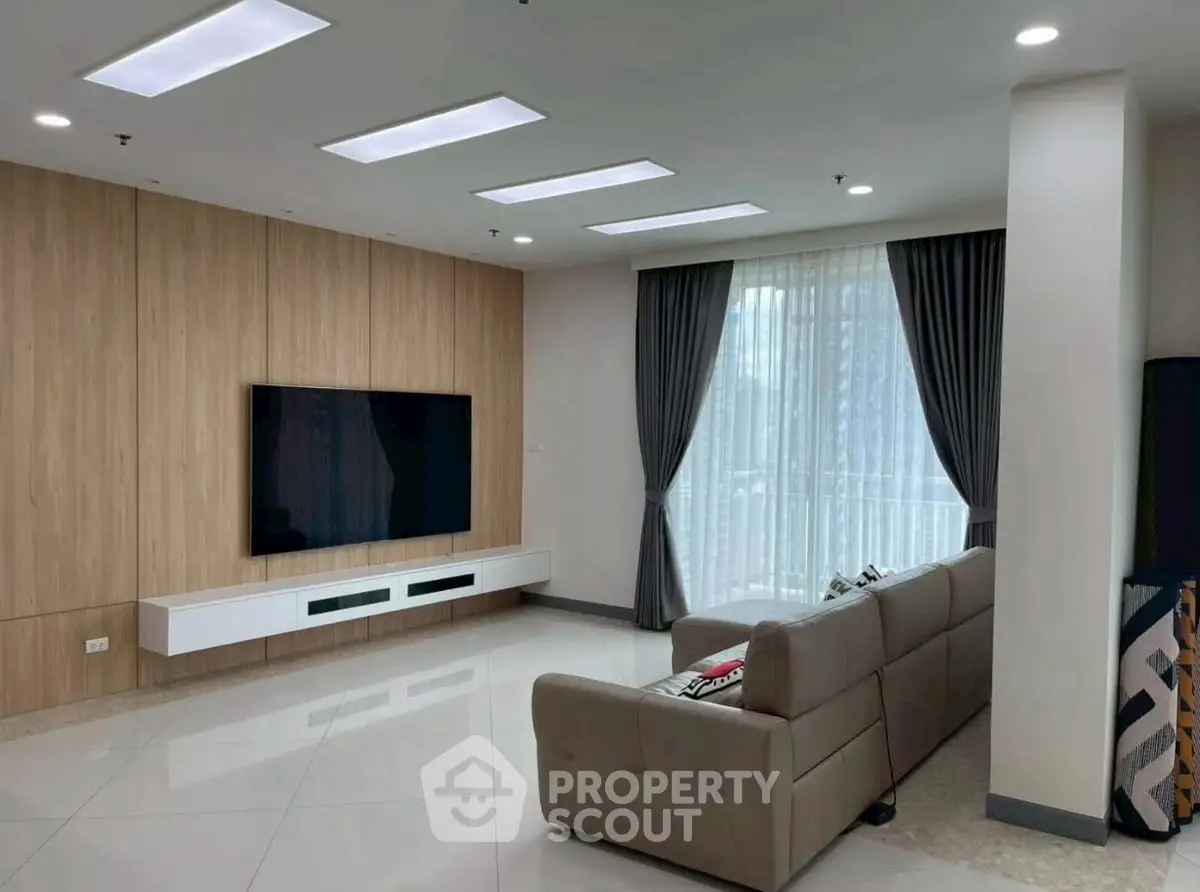 Modern living room with sleek design, large TV, and elegant curtains.