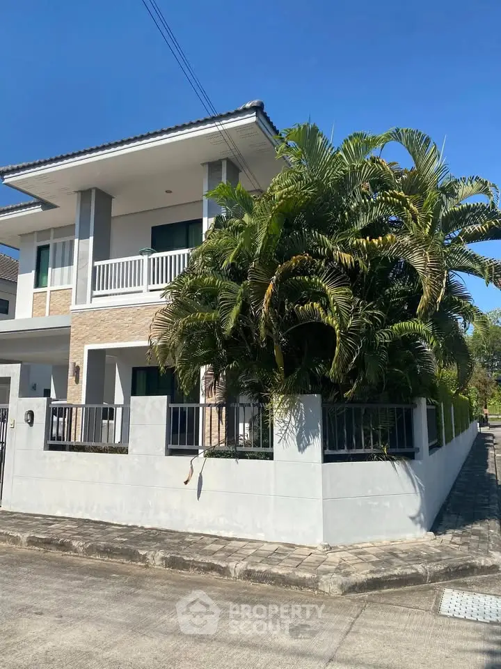 Stunning modern two-story house with lush greenery and spacious balcony in a serene neighborhood.