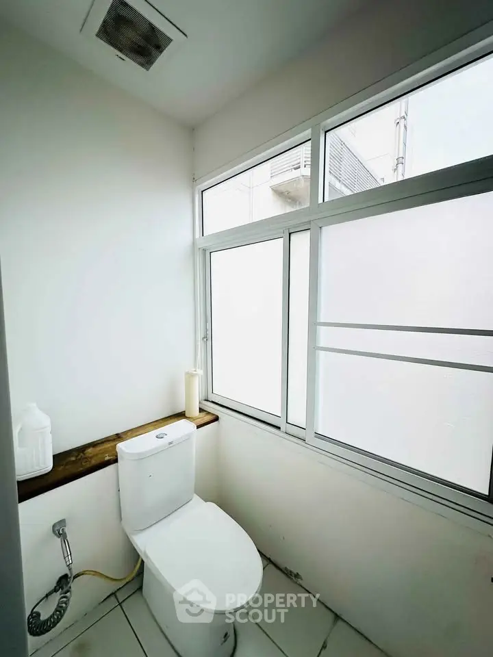 Bright bathroom with large frosted window and modern toilet design.