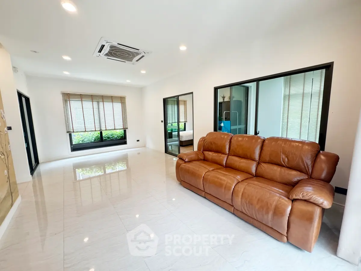 Spacious living room with leather sofa and large windows in modern home