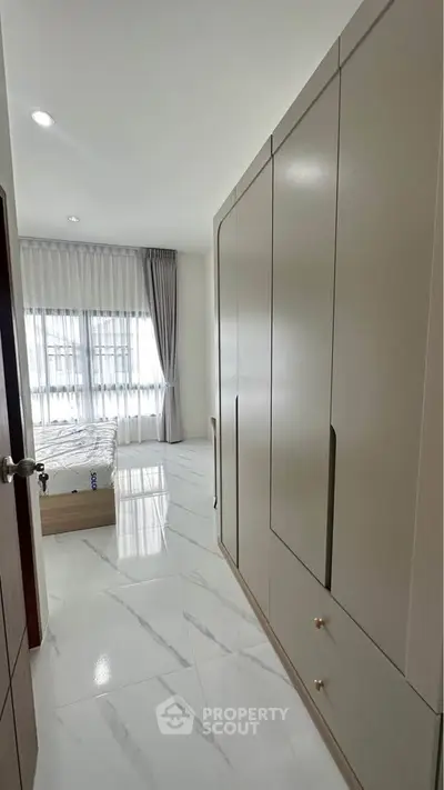 Spacious bedroom with modern wardrobe and large windows for natural light.