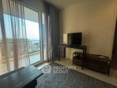 Modern living room with balcony and sea view, featuring sleek furniture and natural light.