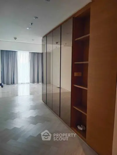Spacious modern living room with elegant wood flooring and large mirrored closet.