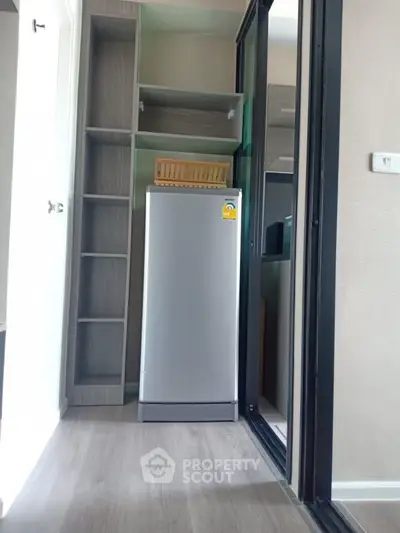 Compact storage area with modern fridge and shelving in sleek apartment