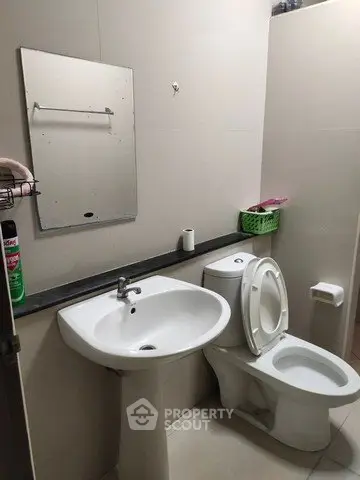 Compact bathroom with pedestal sink and toilet, ideal for small spaces.