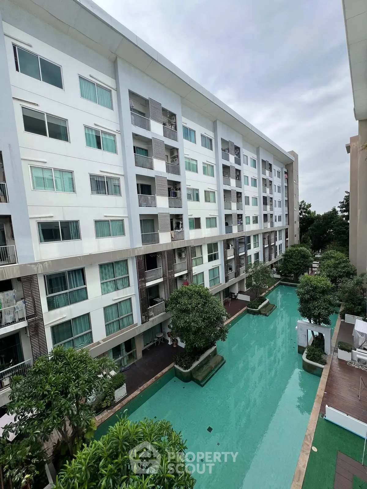 Modern apartment building with pool view and lush greenery, offering a serene living environment.