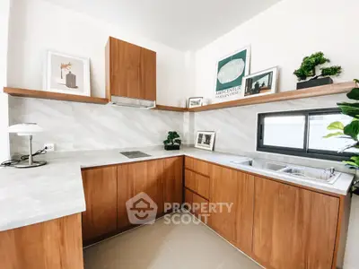 Modern kitchen with sleek wooden cabinets and marble countertops, featuring stylish decor and ample natural light.