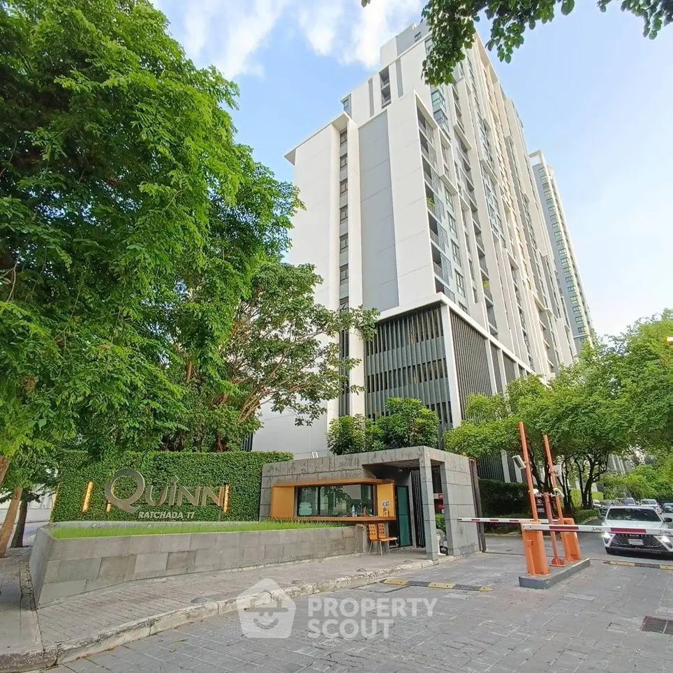 Modern high-rise building with lush greenery and stylish entrance in prime urban location.