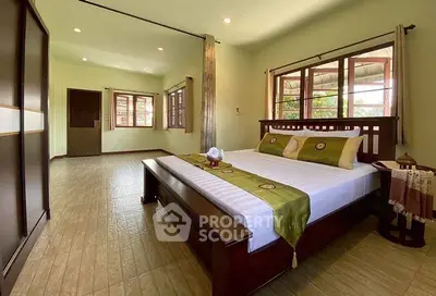 Spacious bedroom with elegant wooden furniture and large windows offering natural light.