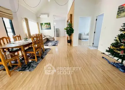 Spacious living and dining area with elegant wooden flooring and festive decor.