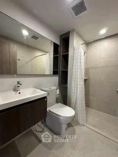 Modern bathroom with sleek fixtures and spacious shower in contemporary apartment.