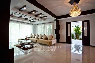 Luxurious living room with elegant chandelier and modern decor, featuring a spacious seating area and large windows.