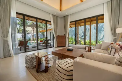 Luxurious living room with large windows opening to a lush garden view, featuring elegant furniture and decor.
