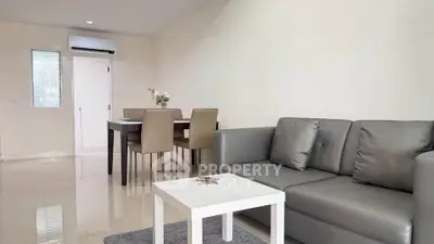Modern living room with sleek gray sofa and dining area in open layout apartment.