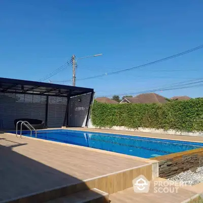 Luxurious outdoor swimming pool with modern deck and privacy hedge