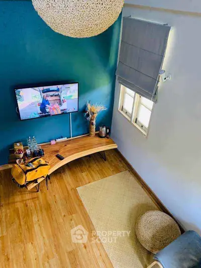 Stylish living room with modern decor and wall-mounted TV, featuring wooden flooring and cozy seating.