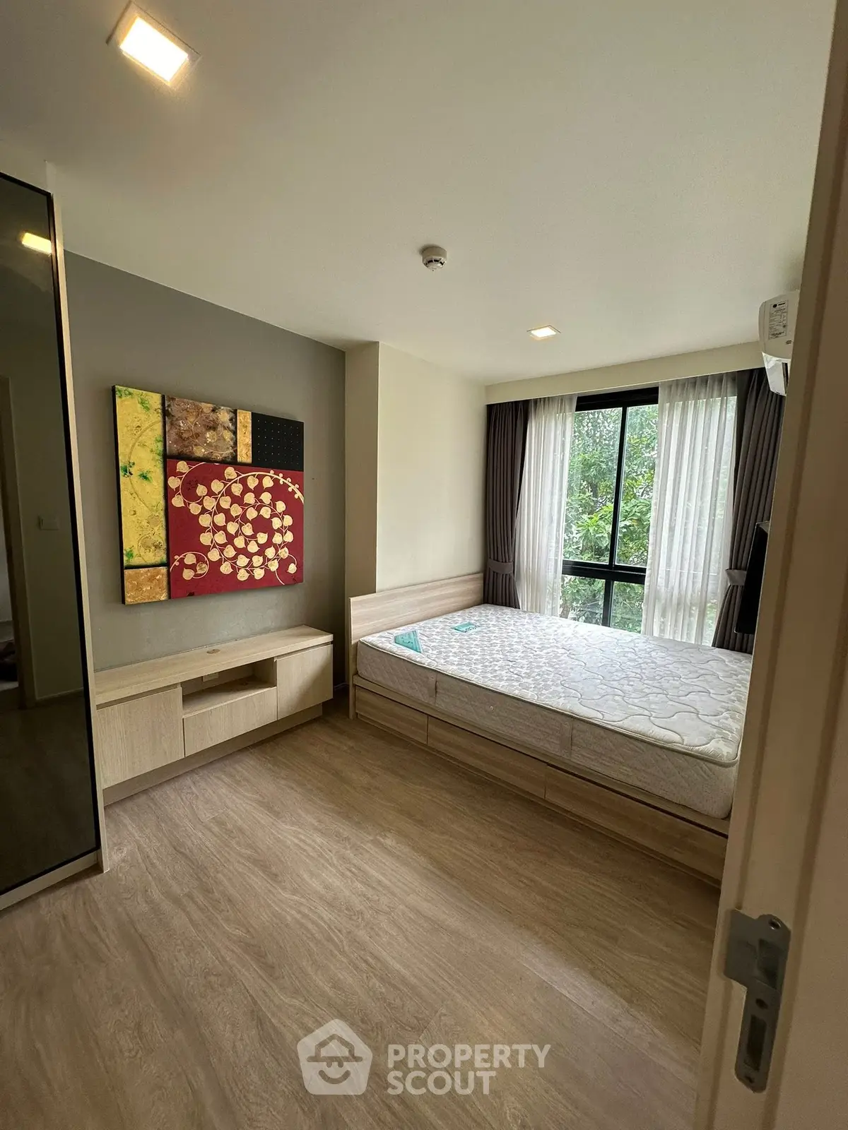 Modern bedroom with large window and stylish decor in a contemporary apartment.