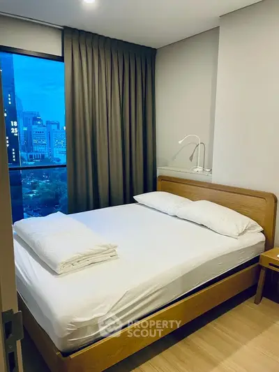 Cozy bedroom with city view, featuring a comfortable bed and modern decor, perfect for urban living.
