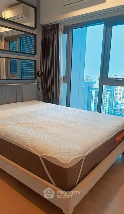 Modern bedroom with large windows and city view, featuring a comfortable bed and stylish decor.