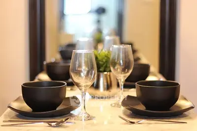 Elegant dining setup with black dinnerware and glassware on a marble table.