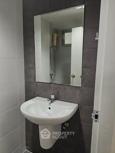 Modern bathroom with sleek sink and mirror, featuring a shower area with contemporary design.