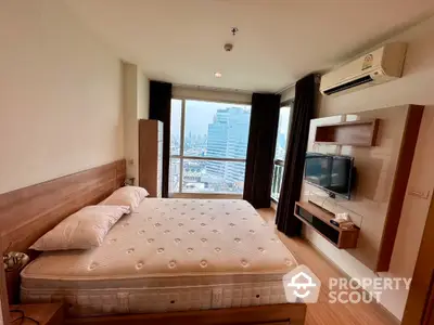 Modern bedroom with city view, featuring a comfortable bed and wall-mounted TV in a high-rise apartment.