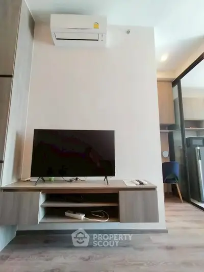 Modern living room with wall-mounted TV and air conditioning in a stylish apartment.