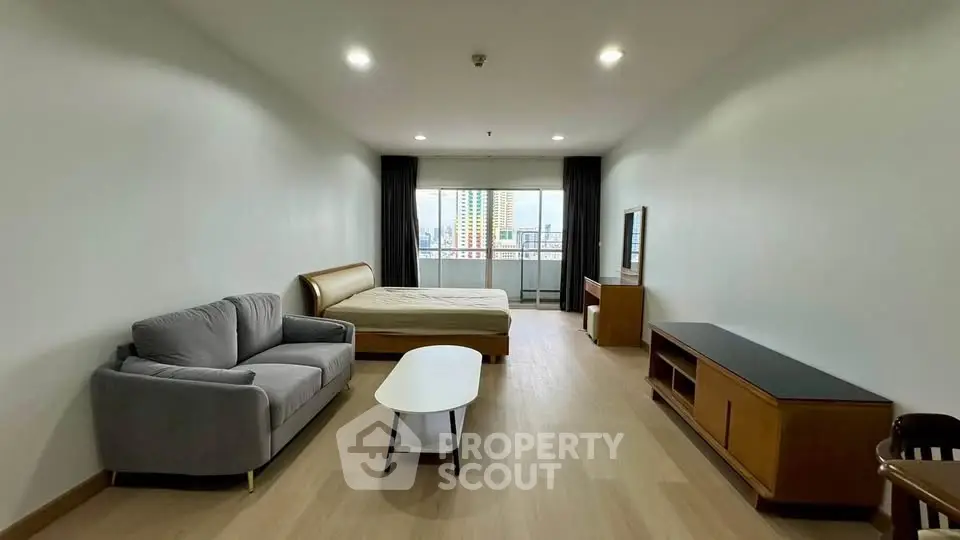 Spacious studio apartment with modern furnishings and city view balcony.
