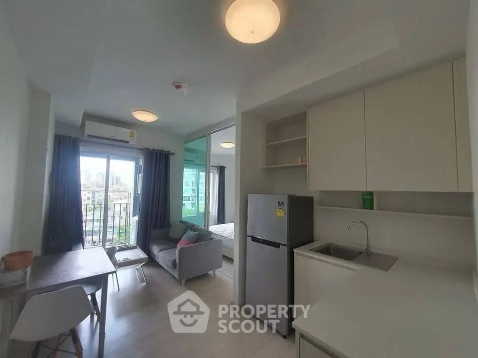 Modern open-layout apartment with kitchen, dining area, and living room, featuring natural light and city views.