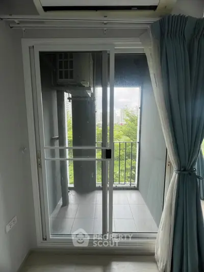 Modern apartment balcony with sliding glass doors and lush green view