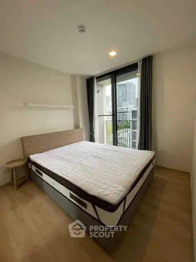 Modern bedroom with large window and city view, featuring a comfortable bed and minimalist decor.