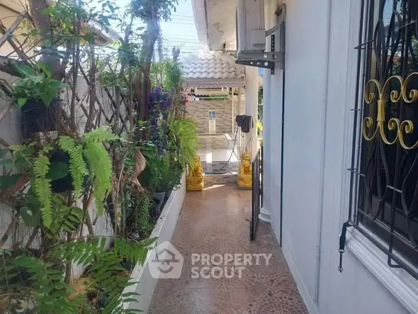 Charming garden pathway with lush greenery and decorative ironwork in a cozy residential setting.