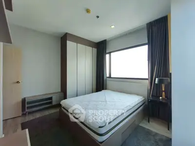 Modern bedroom with large window and stylish furnishings in a contemporary apartment.