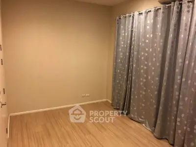 Spacious empty room with wooden flooring and elegant curtains, perfect for customization.