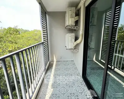 Charming balcony with patterned tiles and lush green view, perfect for relaxation.