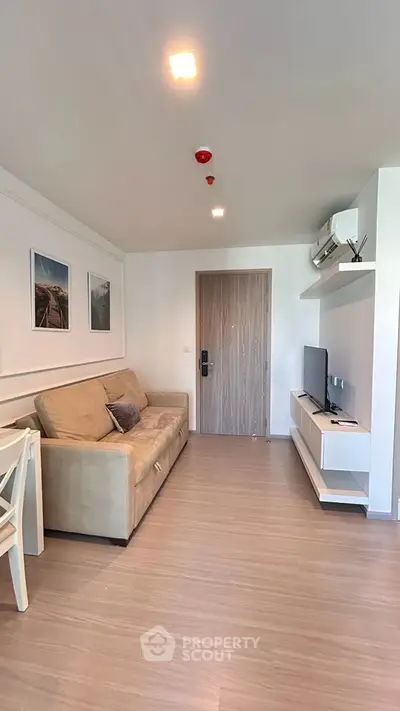 Modern living room with beige sofa, wall-mounted TV, and stylish decor in a cozy apartment.
