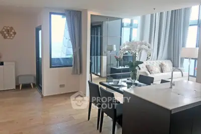 Modern open-plan living room with dining area and large windows in a stylish apartment.