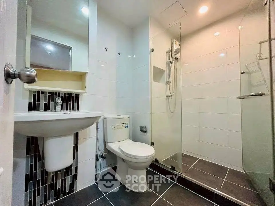 Modern bathroom with sleek design, featuring a glass shower and contemporary fixtures.