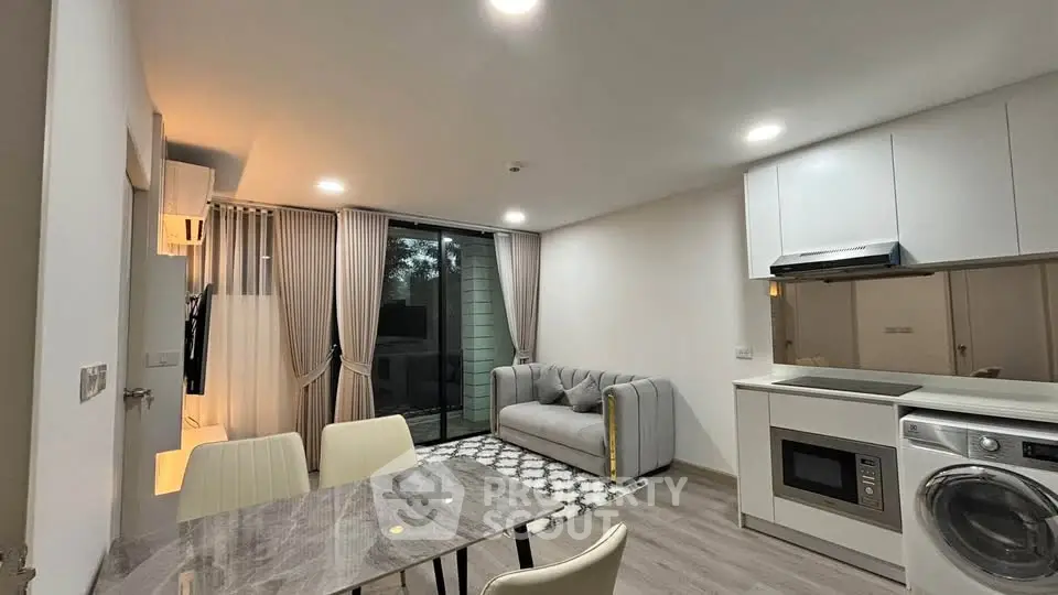 Modern open-plan living room with kitchen, featuring sleek furniture and appliances, ideal for urban living.