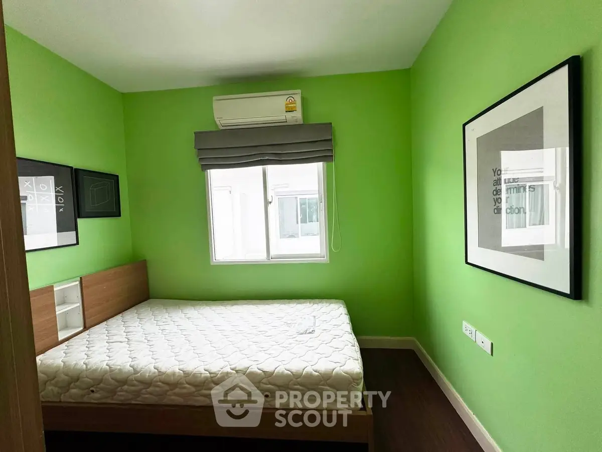 Bright bedroom with green walls, modern artwork, and air conditioning, perfect for a cozy retreat.