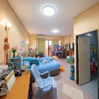 Spacious bedroom with cozy decor and ample natural light, featuring a comfortable bed and organized storage.