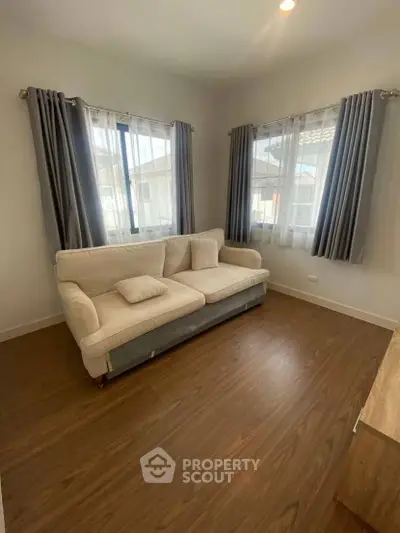 Cozy living room with elegant sofa and natural light from large windows.