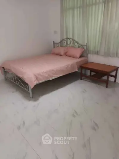 Cozy bedroom with metal bed frame and soft pink bedding, perfect for relaxation.