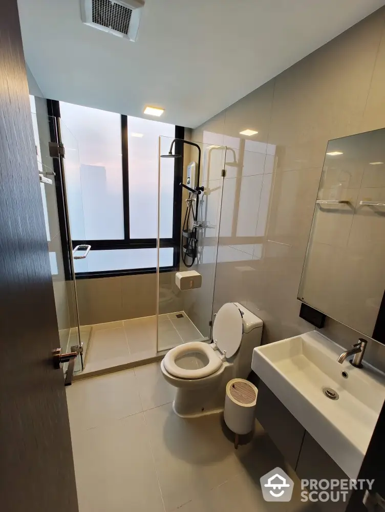 Modern bathroom with glass shower and sleek fixtures in high-rise apartment