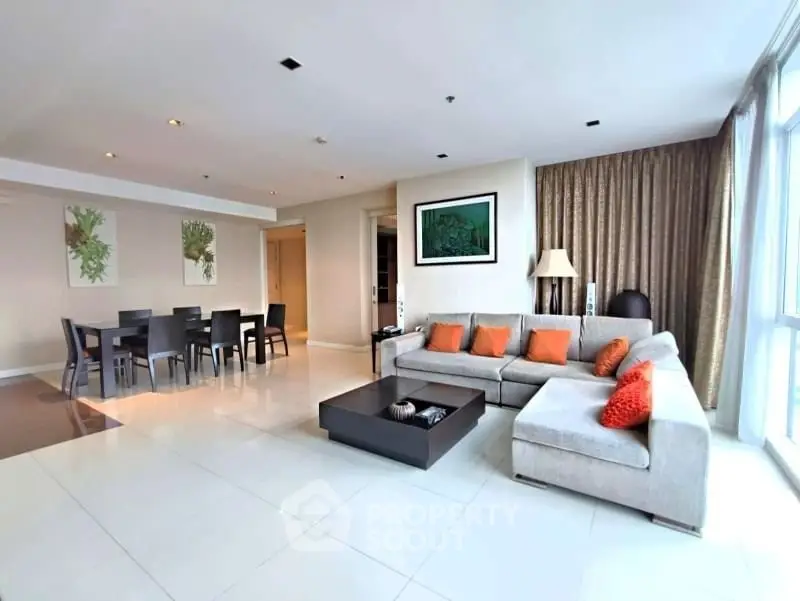 Spacious modern living room with large sectional sofa and dining area, perfect for entertaining.