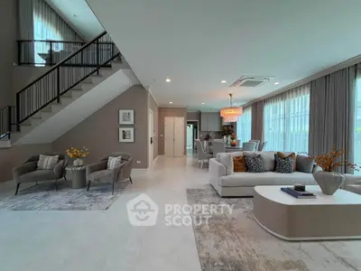 Luxurious open-plan living room with elegant decor and modern staircase in a spacious home.