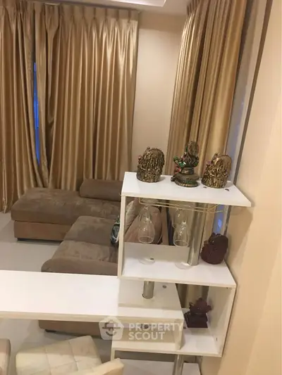 Elegant living room with plush sofa and decorative accents, featuring golden drapes for a luxurious touch.