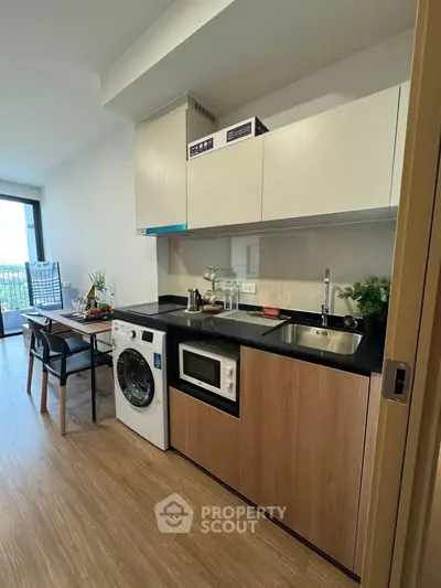 Modern kitchen with washing machine and dining area in open layout apartment